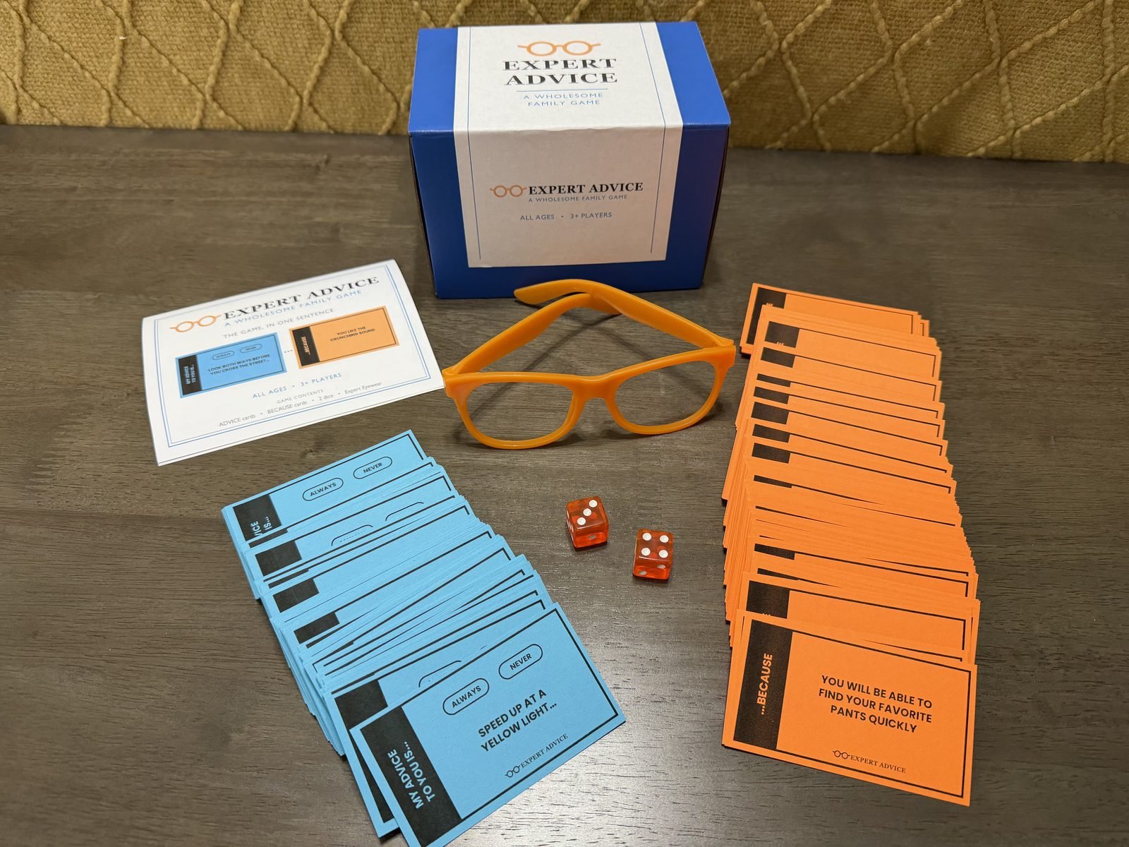 Expert Advice family card game &mdash; full contents: blue ADVICE and orange BECAUSE cards, two dice, Expert Eyewear, rules sheet, and box